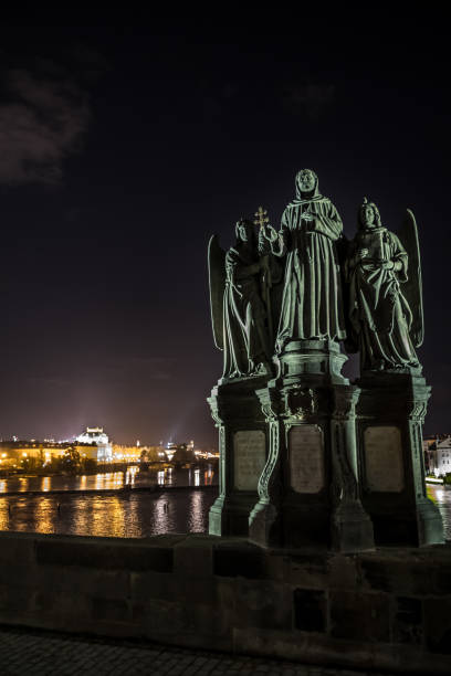 Statue On Charles Bridge And View Over Moldova River And Illuminated Buildings In Prague In The Czech Republic  prague art stock pictures, royalty-free photos & images