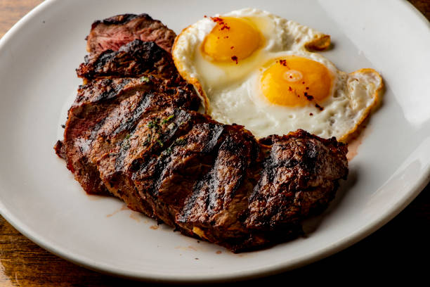 Steak and eggs. Traditional classical American diner or French Bistro brunch item, steak and eggs with tots. Angus steak served medium rare with fried eggs and crispy seasoned home fries. stock photo
