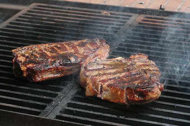 Steak cooking on flame grill stock photo