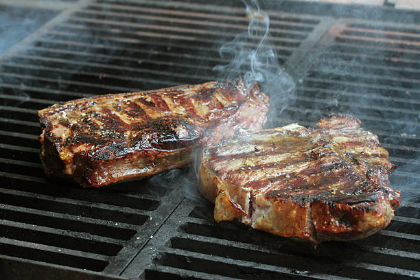 Steak cooking on flame grill stock photo