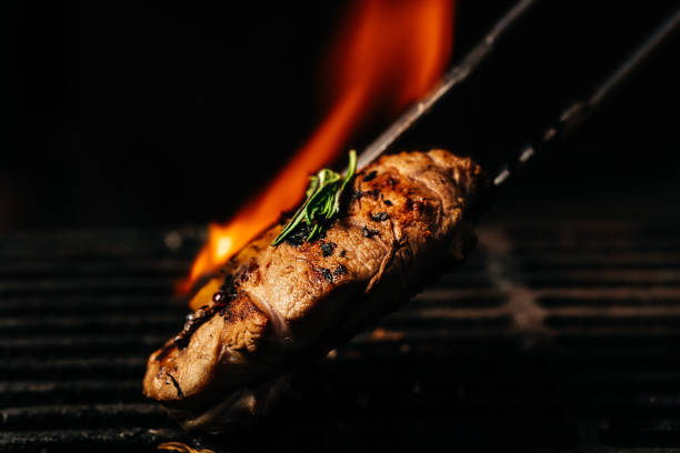 steak on the grill with flames raw beef steak on a bbq grill banner picture - The Tasty Hub