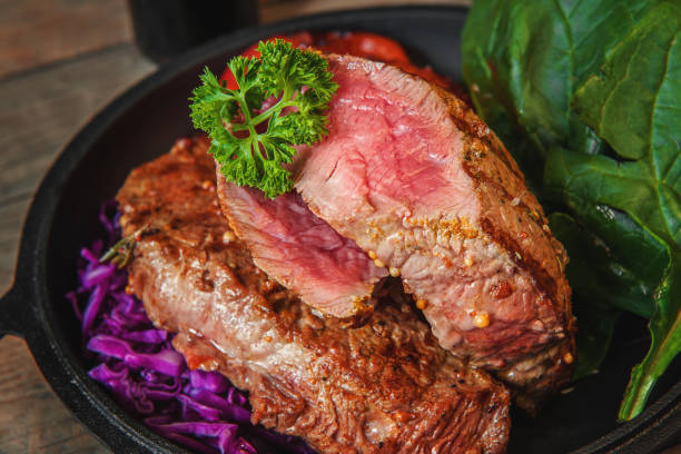 Steak rare with the blood of vegetables tomatoes and spinach grilled in a pan at home on the wooden table. Rustic style. Steak rare with the blood of vegetables tomatoes and spinach grilled in a pan at home on the wooden table. Rustic style. Close up. Crossm Rib Roast stock pictures, royalty-free photos & images