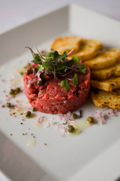 Steak tartare. Classic American restaurant or bistro appetizer classic. Steak grade a Kobe beef, diced, mixed w/ eggs, red onions, olive oil, lemon juice, garlic & capers. Served w/ garlic bread. Fine dining classic appetizer. stock photo