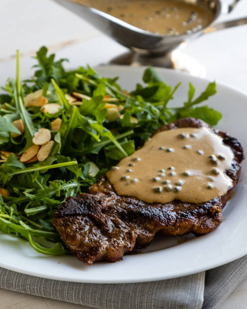 steak with arugula and green peppercorn sauce stock photo