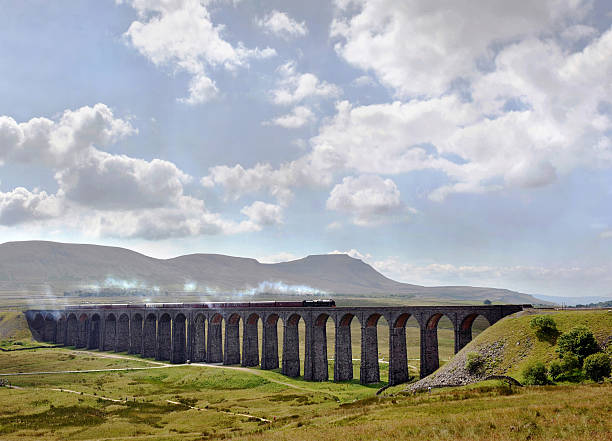 Steam train "A vintage steam train passes over the Ribblehead viaduct (1874) in North YorkshireEngland, UKIt is the longest and most famous viaduct on the Settle-Carlisle Railway, a railway line passing through some spectacular British scenery. The first stone was laid on 12 October 1870 and the last in 1874" northwest england stock pictures, royalty-free photos & images