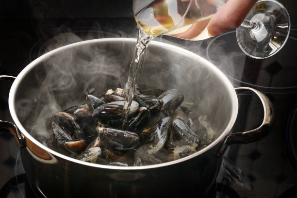 Steaming mussels in a pot are deglazed with white wine, cooking concept for a delicious seafood dish, selected focus stock photo