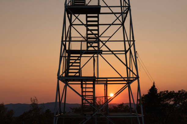 Photo of Steep stairs leading up a mountain fire tower as the sun sets on the horizon. Overlook Mountain, NY