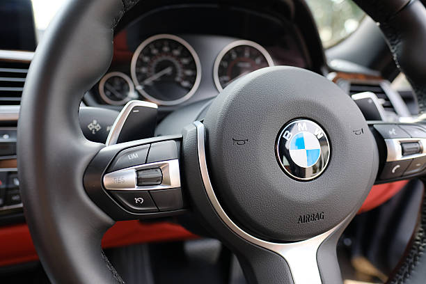 Steering wheel view of a BMW sports coupe model Saint Ives, Cambridgeshire UK - April 1 2016: Close up view of the new style, sports steering wheel showing its paddle style gear changer from a 4 Series sports coupe. bmw stock pictures, royalty-free photos & images