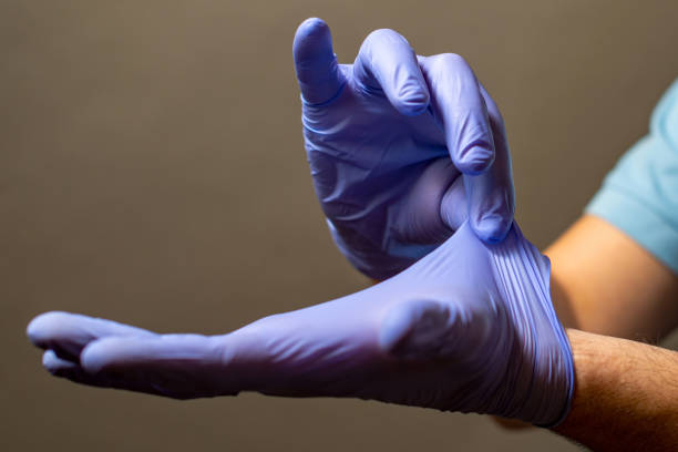 schritt der hand wegwerfen blaue einweghandschuhe medizinisch, isoliert auf weißem hintergrund. infektionskontrollkonzept. - handschuh stock-fotos und bilder