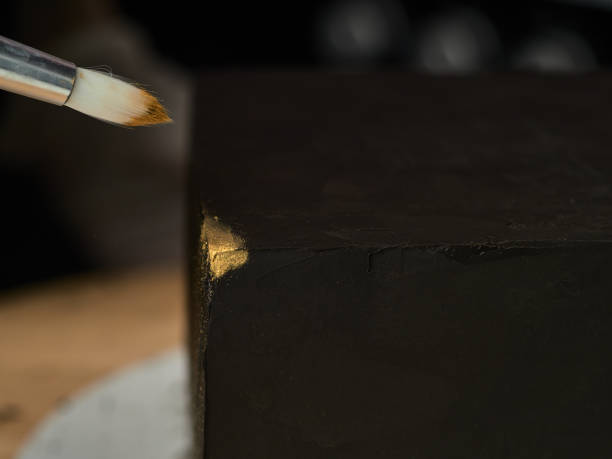 Step-by-step preparation of black designer cake. The confectioner decorates a black cake, gold food paint. stock photo