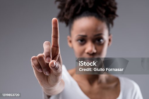 istock Stern focused young woman holding up her index finger 1319853720