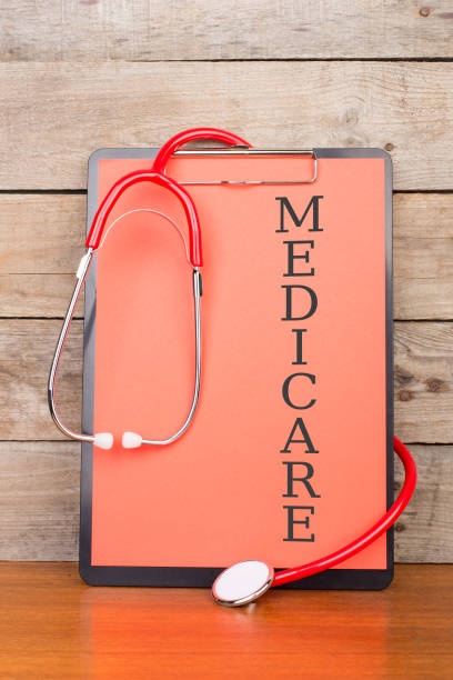 stethoscope and clipboard with text "MEDICARE" on wooden desk background stock photo