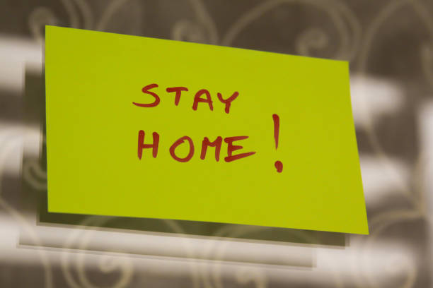 Sticky note on window with Stay Home writing text message stock photo