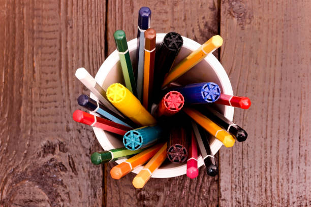 Still life, business, education concept. Crayons and markers in a Cup on a wooden table. Top view, copy space background. stock photo