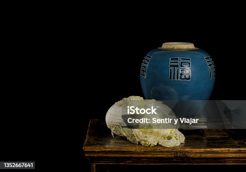 istock Still life of a Chinese cabbage and a Chinese blue antique porcelain jar from Qing Dynasty on wooden table against black background 1352667641