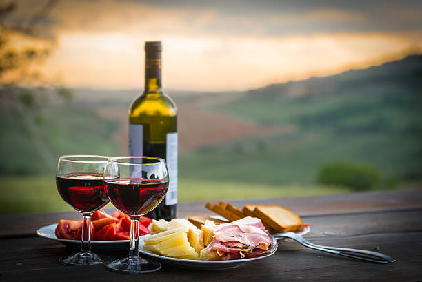 still life red wine  ,cheese and prosciutto - sunset dining stockfoto's en -beelden