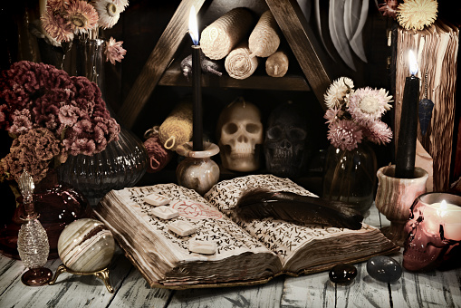 Still life with old grimoire book of magic spells, runes and evil candles on witch table. Esoteric, gothic and occult background, No foreign symbols, all signs are fantasy one.