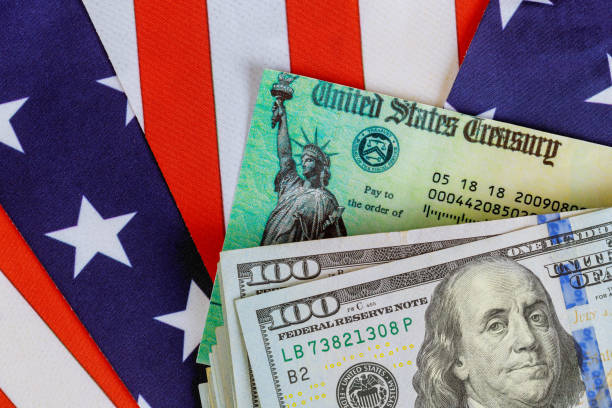 stimulans economische belastingaangifte check en us 100 dollar biljetten valuta met amerikaanse vlag - taxes, betalen stockfoto's en -beelden