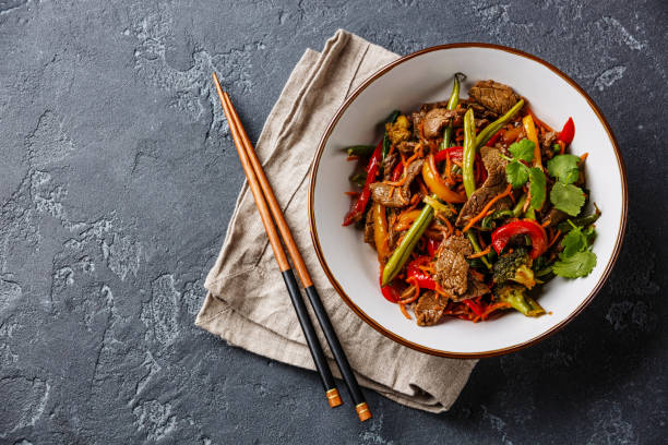 Stir fry beef with vegetables in bowl Stir fry beef with vegetables in bowl on dark stone background chopsticks stock pictures, royalty-free photos & images