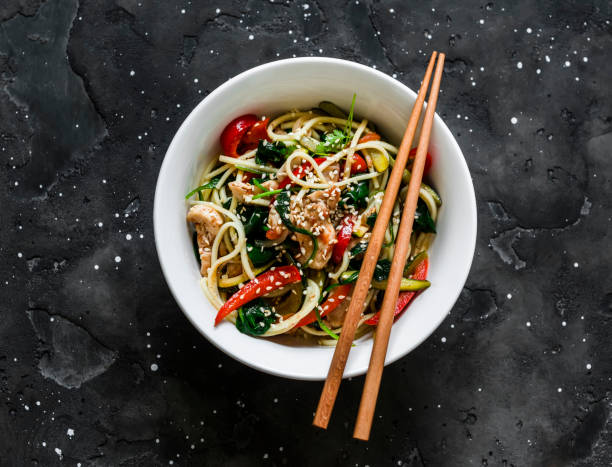 stir fry vegetables zucchini, pepper, spinach and chicken with egg noodles on a dark background, top view - wok stockfoto's en -beelden