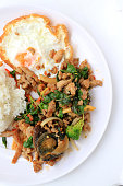 istock Stir-fried basil leave with minced pork, chicken, fried preserved egg and carrot, yellow corn, Broccoli with rice and fried egg in white dish on white background. Thai style food. 953447406