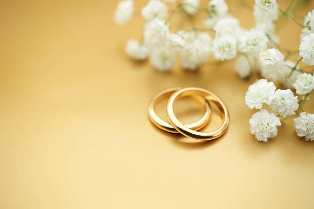 Stock Photo Gold Wedding Rings Elegant wedding invitation:  rings and flowers on a golden background. wedding ring stock pictures, royalty-free photos & images