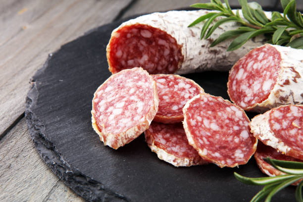 Stone cutting board with sliced salami on it stock photo
