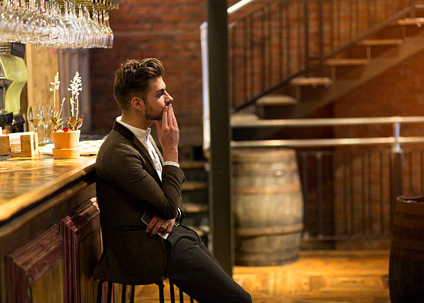 Stood Up A young man is dressed smarty at a bar waiting, he looks fed up as if he has been stood up on a date. One hand is on his face and the other is holding his smart phone. one man only stock pictures, royalty-free photos & images