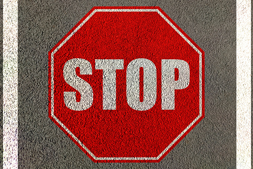Stop sign painted on asphalt road lane for stop traffic movement a signal for danger
