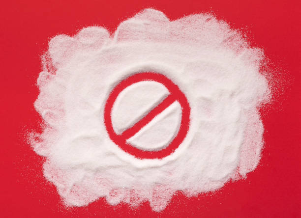 Stop prohibition sign on white sugar background Stop prohibition sign on sugar. Diet and weight loss, refusal of sweet. Diabetes problems, harm from eating, dependence on flavoring. Challenge. sugar food stock pictures, royalty-free photos & images