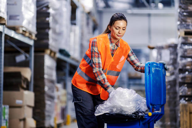 A storage worker putting garbage into a recycle bin. stock photo