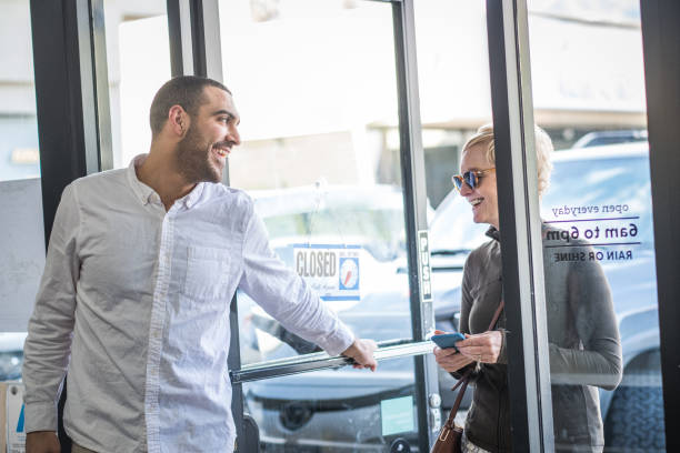 Store Owner Opens Door for Customer at Local Coffee Shop stock photo