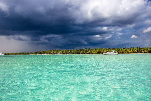 Storm with dark blue dramatic sky coming to tropical island Saona in Dominican Republic in Caribbean Sea as dramatic tropical scenery stock photo