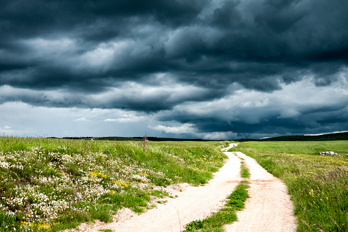 Dramatic stormy dark cloudy sky over field and footpath. Natural photo.