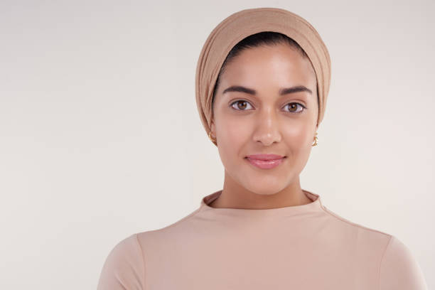 Straight faced and confident Studio shot of an attractive young woman wearing a headscarf smiling at the camera against a beige background arab culture stock pictures, royalty-free photos & images