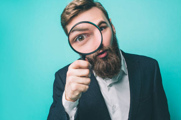 Strange man is looking straight through the loupe. He wonders. Isolated on blue background. stock photo