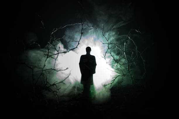 strange silhouette in a dark spooky forest at night, mystical landscape surreal lights with creepy man. Toned strange silhouette in a dark spooky forest at night, mystical landscape surreal lights with creepy man evil photos stock pictures, royalty-free photos & images