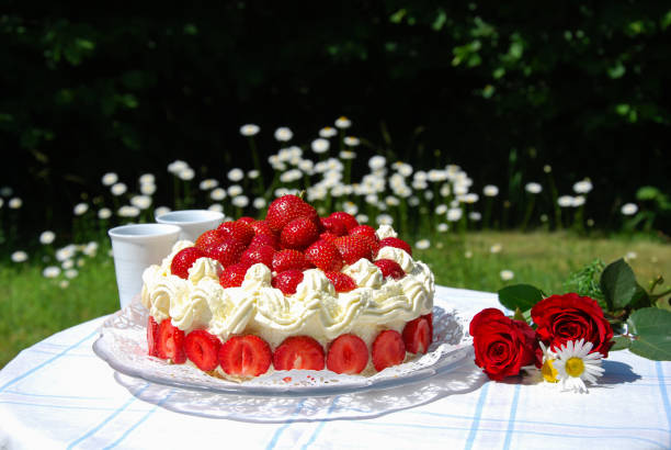 Strawberry cake and two mugs on a garden table stock photo