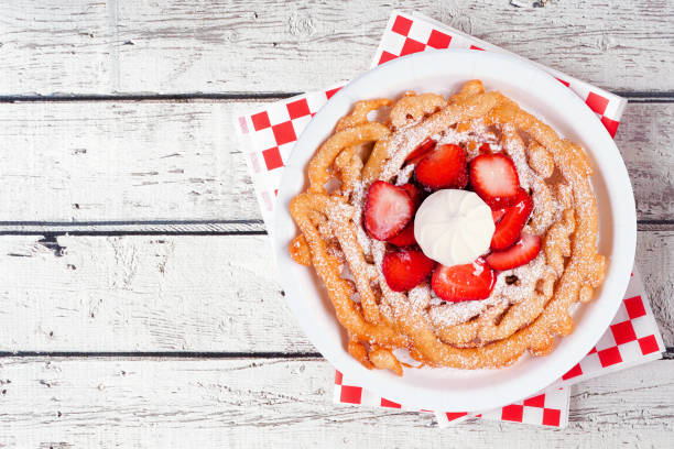 Strawberry funnel cake above view over a white wood background stock photo