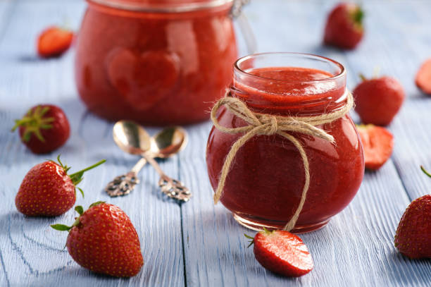 Strawberry jam in glass jar on wooden background. stock photo