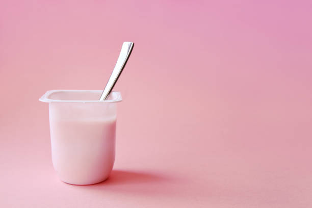 Strawberry pink yoghurt with spoon in it. Minimal style. stock photo
