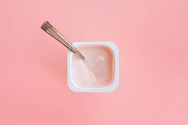Strawberry pink yogurt with spoon in it. Flat lay. stock photo
