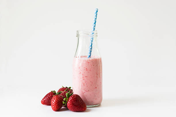 strawberry smoothie horizontal A smoothie made with yogurt and strawberries with juice.  Served in a glass jug with a blue straw and a bunch of fresh, ripe strawberries on the side. strawberry smoothie stock pictures, royalty-free photos & images