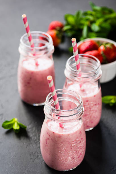 Strawberry smoothie in bottles with drinking straw Strawberry smoothie in bottles with drinking straw. Selective focus. Healthy lifestyle, fitness, detox, dieting, clean eating, vegan, vegetarian concept strawberry smoothie stock pictures, royalty-free photos & images