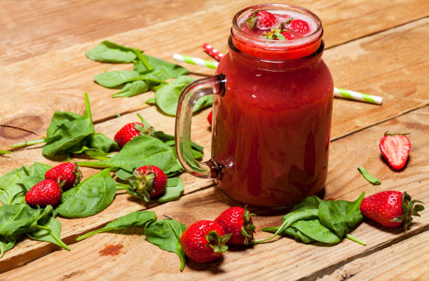 Strawberry smoothie or milkshake in a jar and spinach leaves on wooden background. Strawberry smoothie or milkshake in a jar and spinach leaves on wooden background, healthy food for breakfast and snack strawberry smoothie stock pictures, royalty-free photos & images