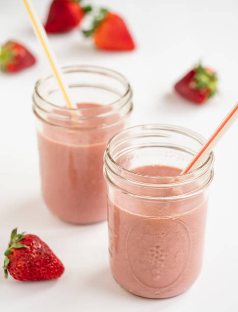 Strawberry smoothie Strawberry smoothie in glass jars on a white surface. strawberry smoothie stock pictures, royalty-free photos & images