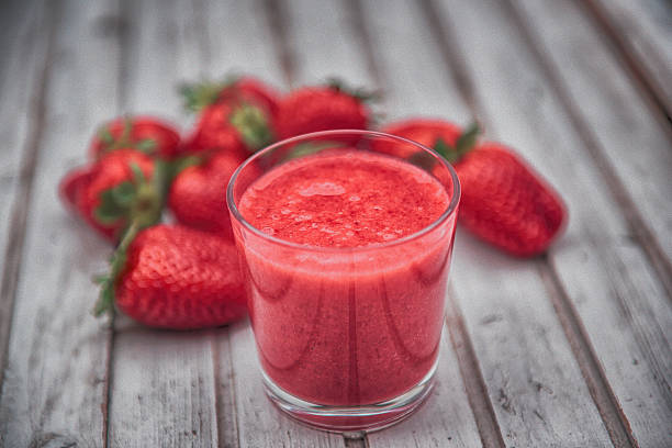 Strawberry Smoothie Healthy and  fresh strawberry smoothie on a wooden table with fresh organic strawberries. strawberry smoothie stock pictures, royalty-free photos & images