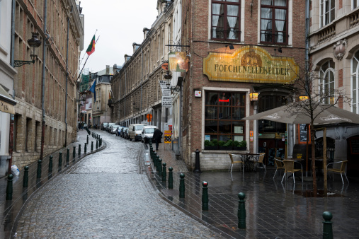 Brussels, Belgium - January 31, 2013: Wet winter day on Rue du Chene, near the location of the famous Manneken Pis sculpture. On the right is Poechenellekelder pub, and up the street are several pedestrians.