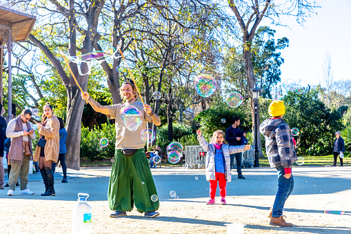 15/12/2019, in Parc de La Ciutadella, Barcelona, Spain: A street artist makes a soap bubble show for children to receive donations from their parents.