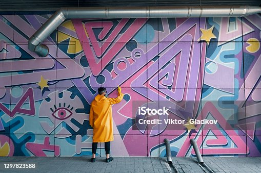 istock Street artist painting colorful graffiti on wall 1297823588